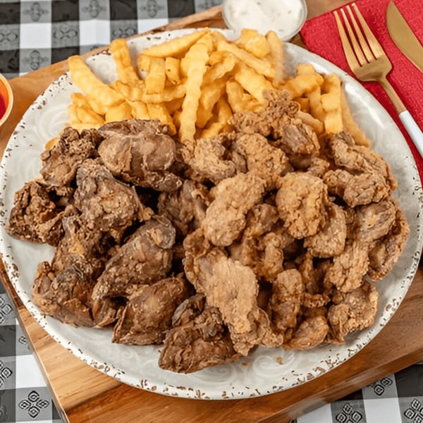 A large plate of G'Ville Seafood N' Chicken fried gizzards and crispy french fries.